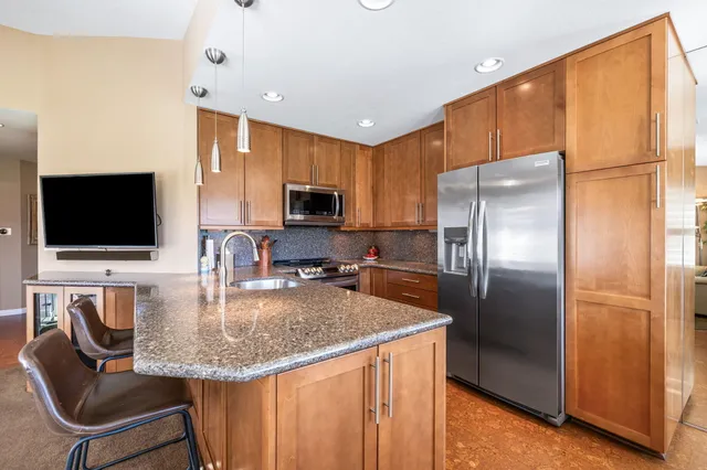 a kitchen with stainless steel appliances granite countertop a refrigerator a stove a microwave oven a sink with island and chairs