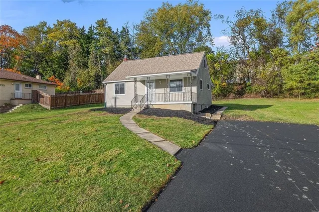 a view of a house with a big yard plants and large trees