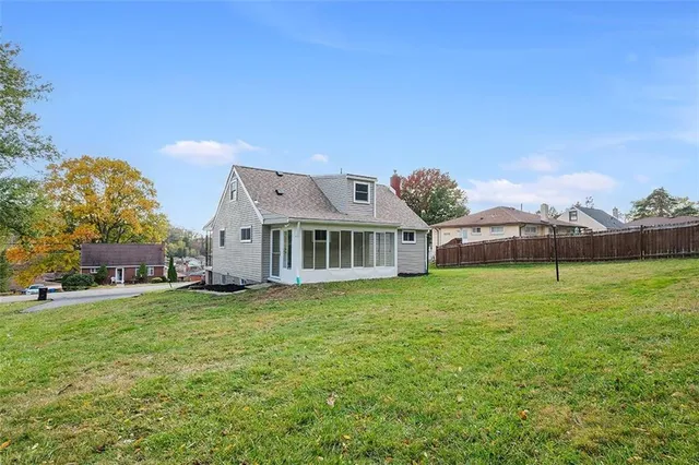 a house that is sitting in the grass with large trees and plants