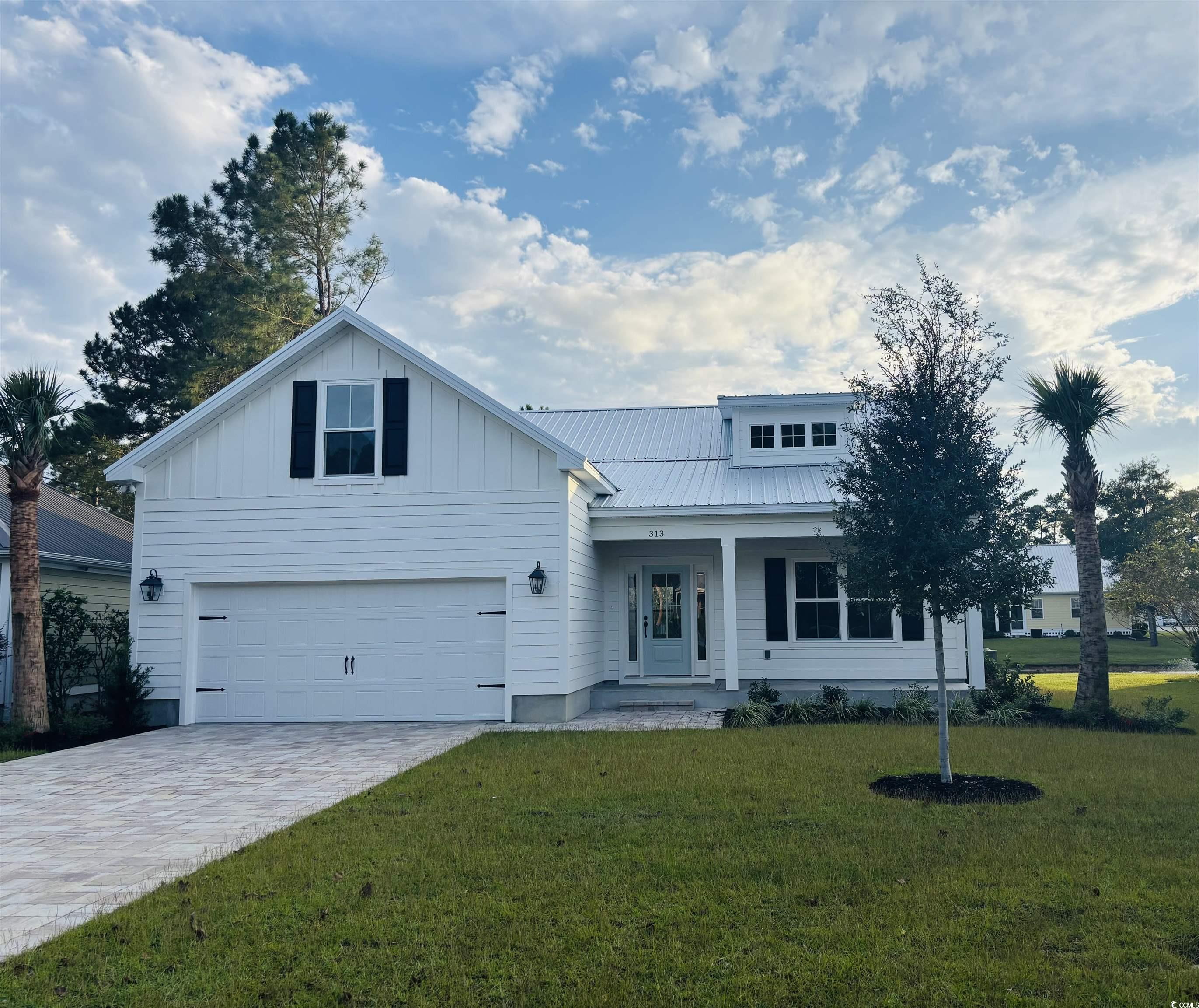 313 Goddard Lane Murrells Inlet, SC 29576 - Photo 1 of 7 View of front of home with a porch, decorative driveway, a front lawn, a garage, and board and batten siding