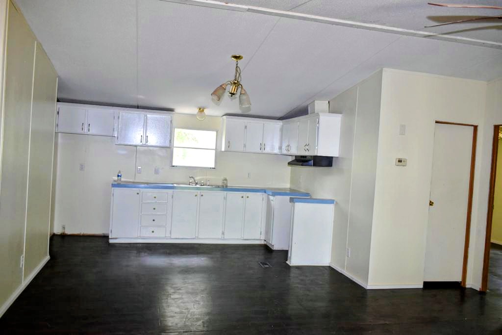 8607 Burleson Manor Road, Unit A Manor, TX 78653 - Photo 3 of 11 a kitchen with granite countertop white cabinets a sink a window and stainless steel appliances