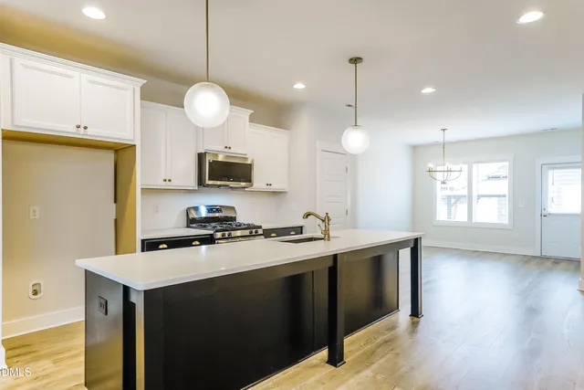 a kitchen with stainless steel appliances granite countertop a sink a stove a refrigerator and a wooden floor