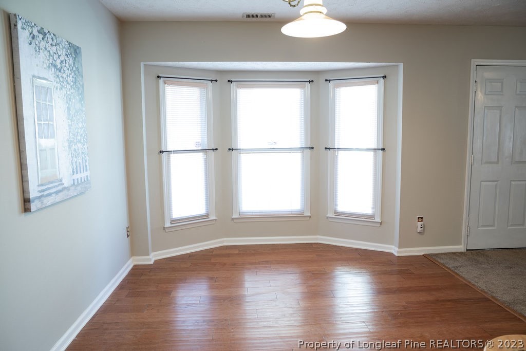 5804 Bibar Road Fayetteville, NC 28304 - Photo 9 of 37 an empty room with wooden floor and windows