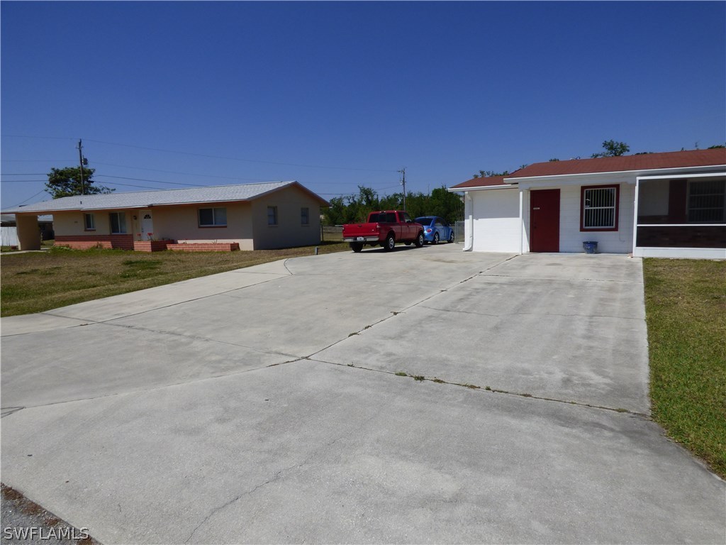301 Davis Road Lehigh Acres, FL 33936 - Photo 4 of 29 a front view of a house with a yard and a garage
