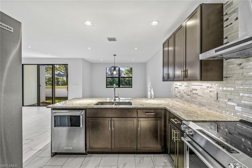 7841 Bristol Circle Naples, FL 34120 - Photo 3 of 28 a kitchen with stainless steel appliances granite countertop a sink stove and cabinets