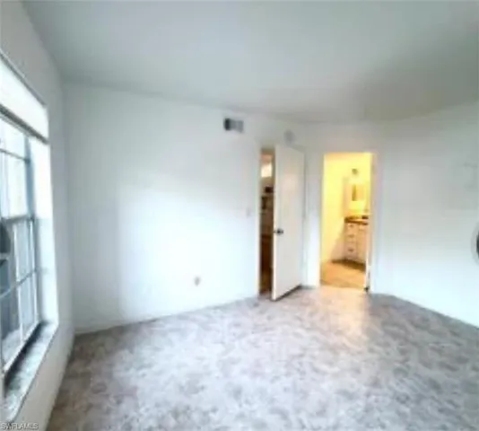 an empty room with a window and a kitchen