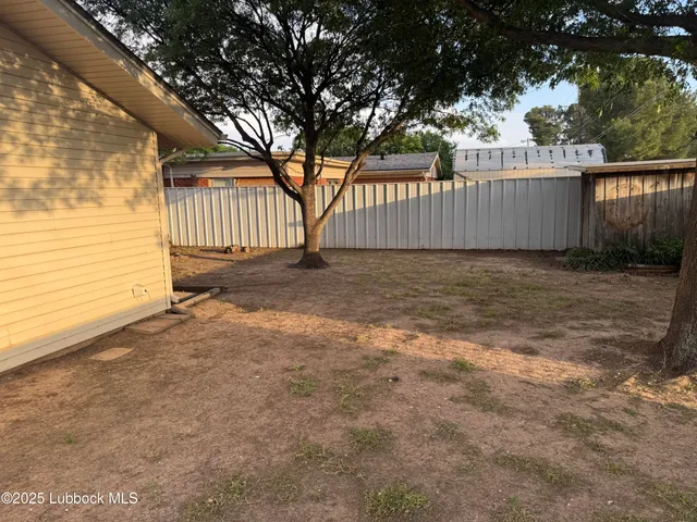 a view of a yard with wooden fence and a large tree