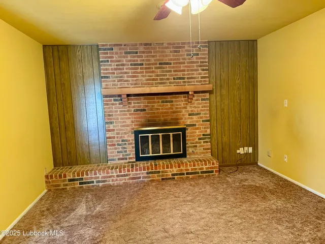 a view of an empty room with a fireplace and a chandelier fan