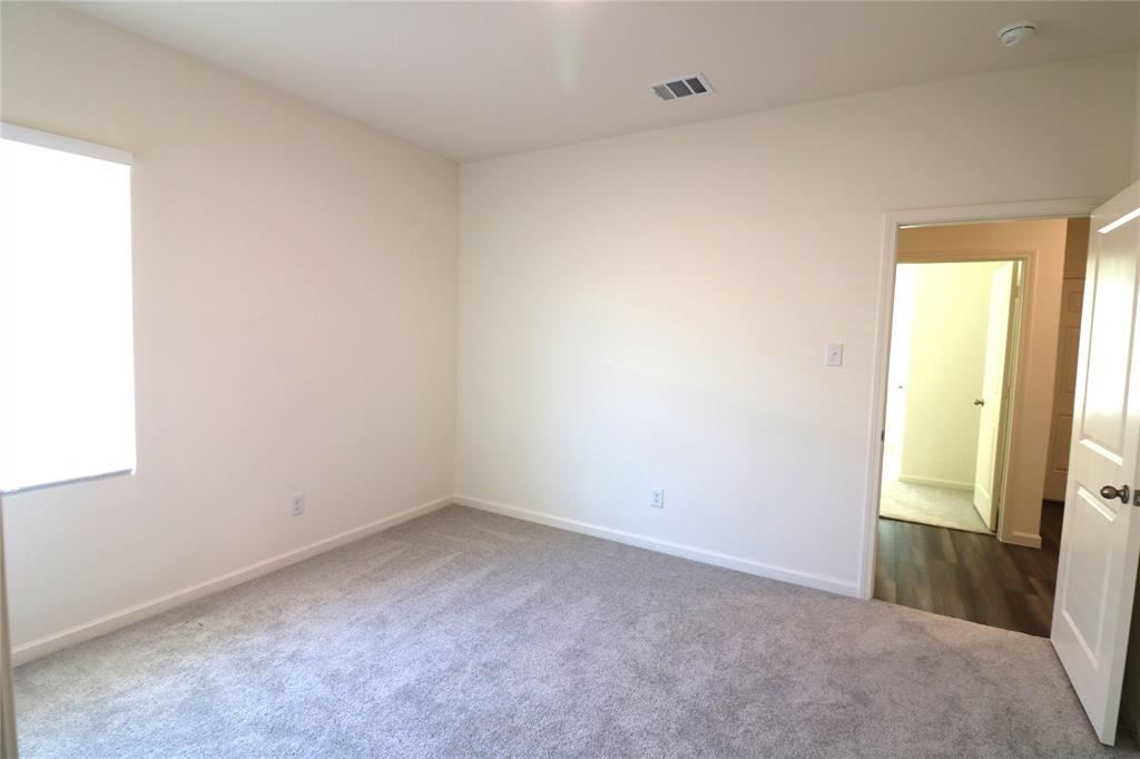 1301 Elliott Road Howe, TX 75459 - Photo 21 of 27 Carpeted room with white walls, a window with a roller shade, and a doorway opening to wood-finish flooring