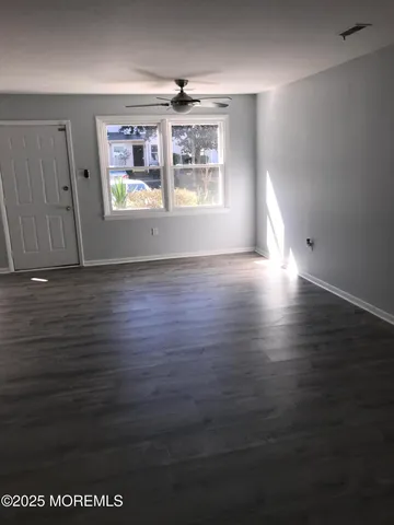 an empty room with wooden floor chandelier and windows