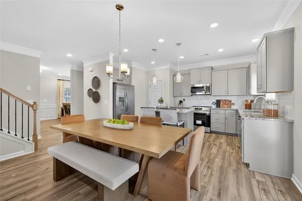 a kitchen with stainless steel appliances granite countertop a refrigerator a sink dishwasher a stove and white countertops with wooden floor