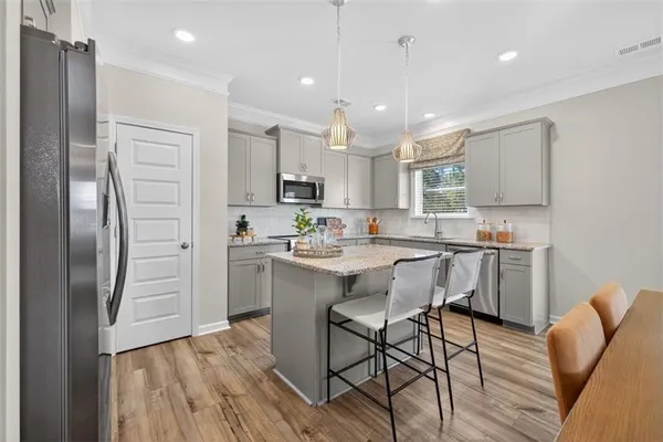 a kitchen with a dining table cabinets and wooden floor