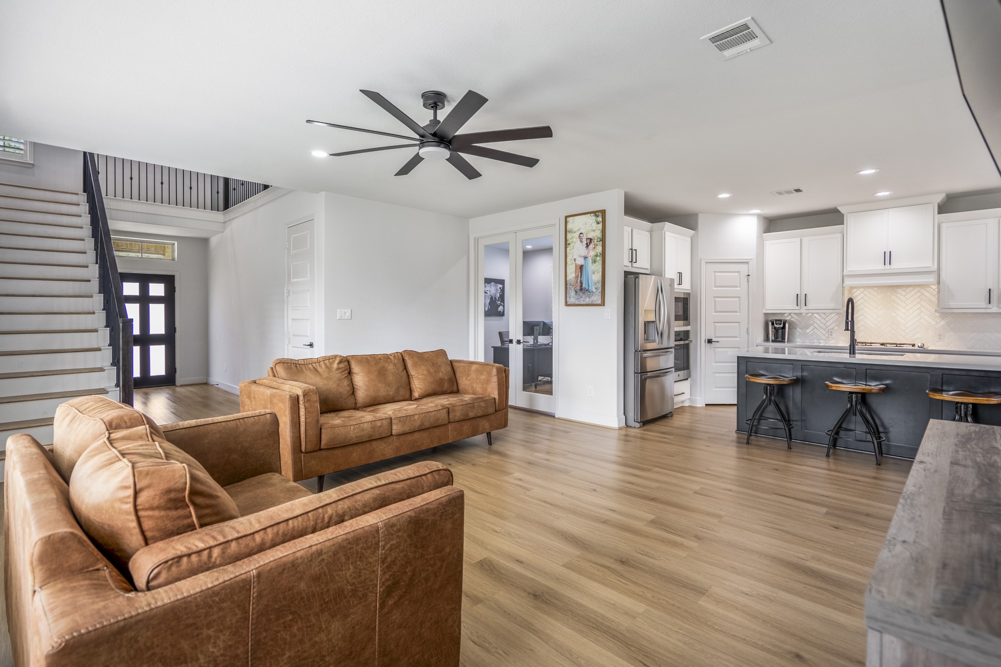 304 Mullins Court Montgomery, TX 77316 - Photo 3 of 50 This modern open-concept living area features sleek LVP floors, a stylish kitchen with white cabinets and stainless-steel appliances, and a cozy seating area. The space is bright, with a contemporary feel.