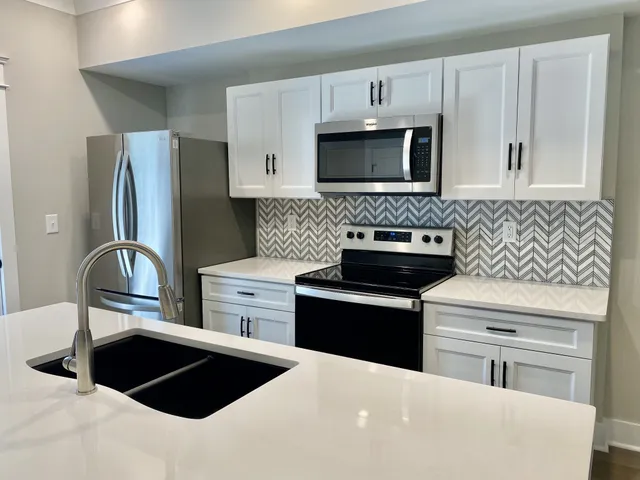 a kitchen with stainless steel appliances a white refrigerator a stove a sink and a microwave