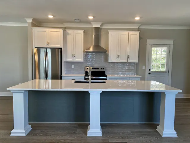 a kitchen with kitchen island granite countertop a sink a stove and refrigerator