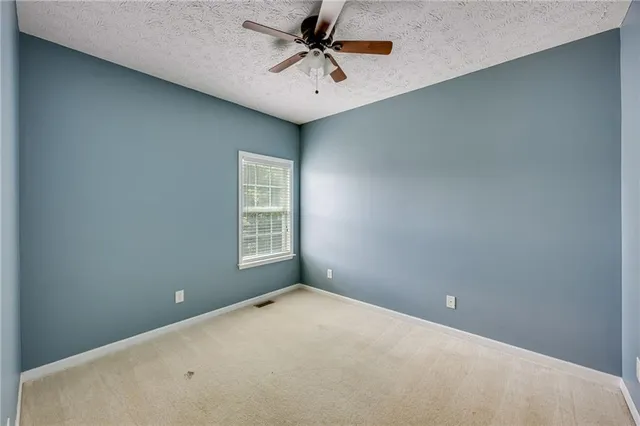 an empty room with a ceiling fan and window