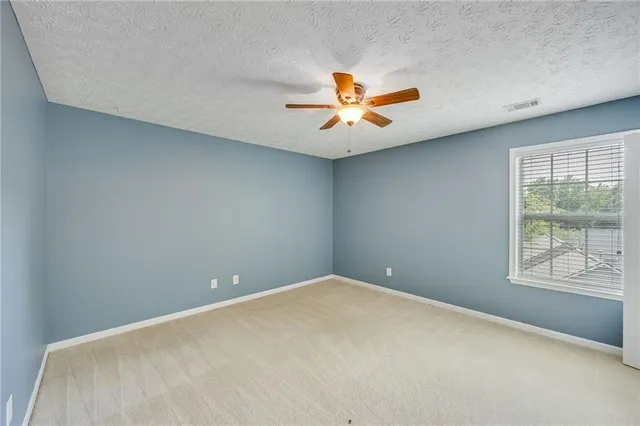 an empty room with a window and a fan