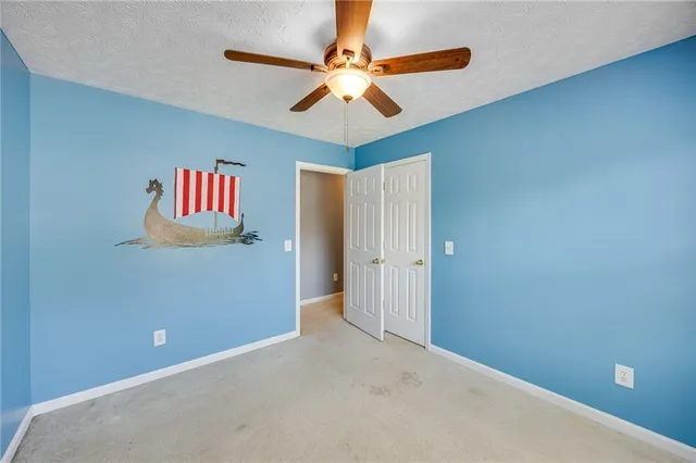 an empty room with closet and fan