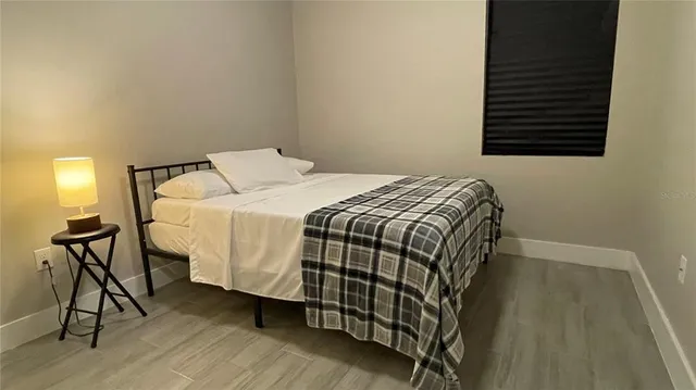 a bedroom with a bed a dresser and wooden floor