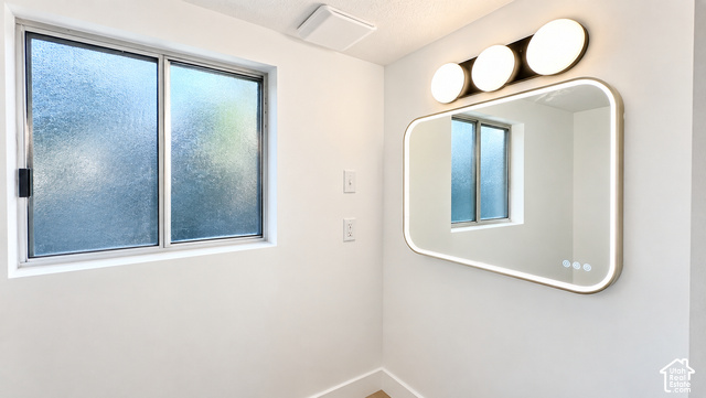 342 East 600 North Logan, UT 84321 - Photo 11 of 19 Frosted glass window, integrated LED mirror, modern vanity lighting, white painted walls, and ceiling-mounted exhaust fan