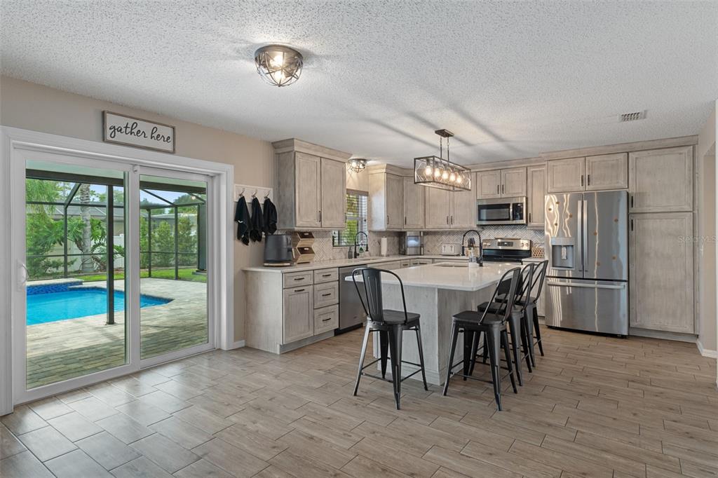 2451 Deltona Boulevard Spring Hill, FL 34606 - Photo 11 of 68 a kitchen with refrigerator a sink and chairs