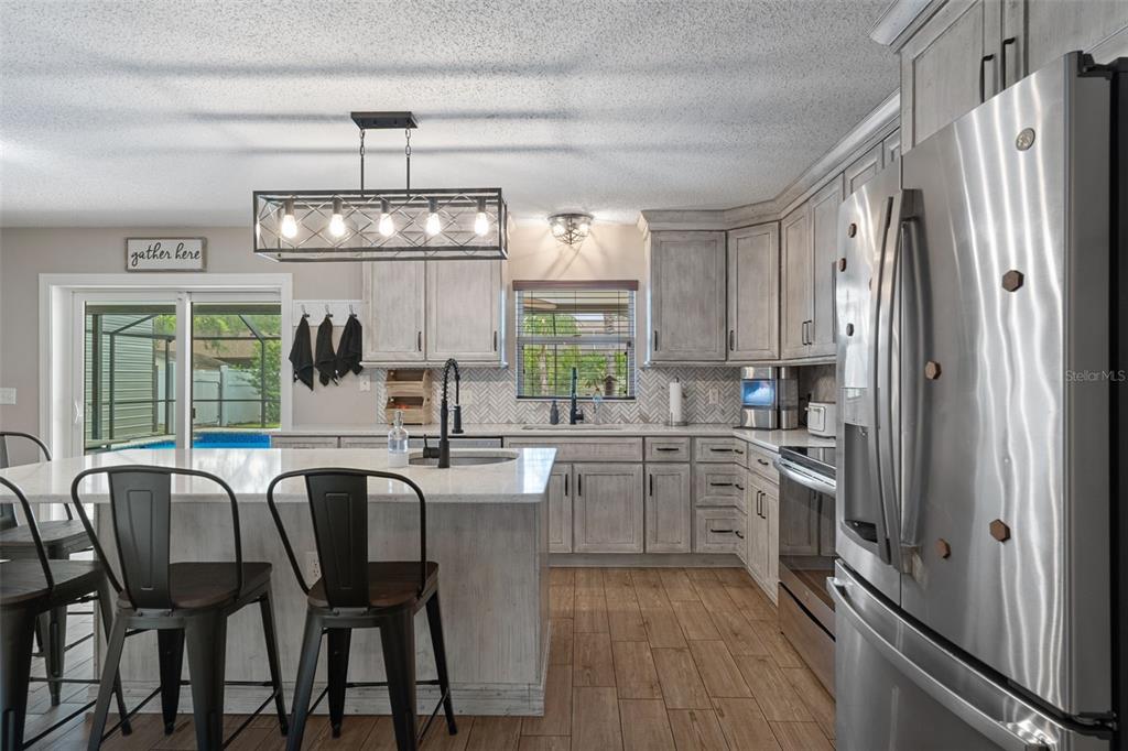 2451 Deltona Boulevard Spring Hill, FL 34606 - Photo 15 of 68 a kitchen with stainless steel appliances granite countertop a stove top oven a sink dishwasher a dining table and chairs with wooden floor