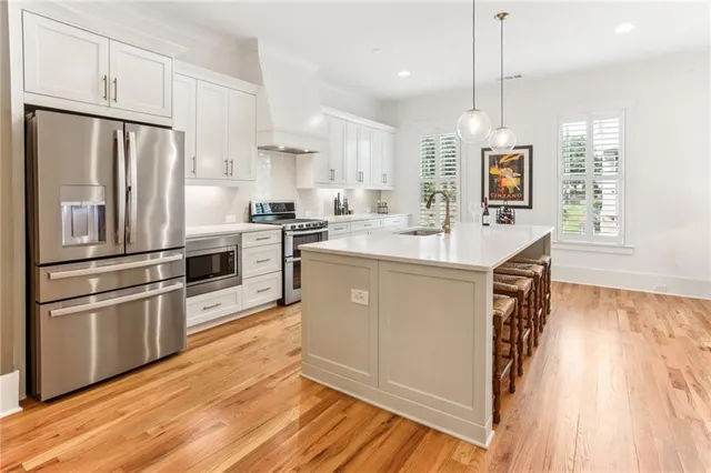 a kitchen with stainless steel appliances granite countertop a refrigerator a stove and a wooden floors