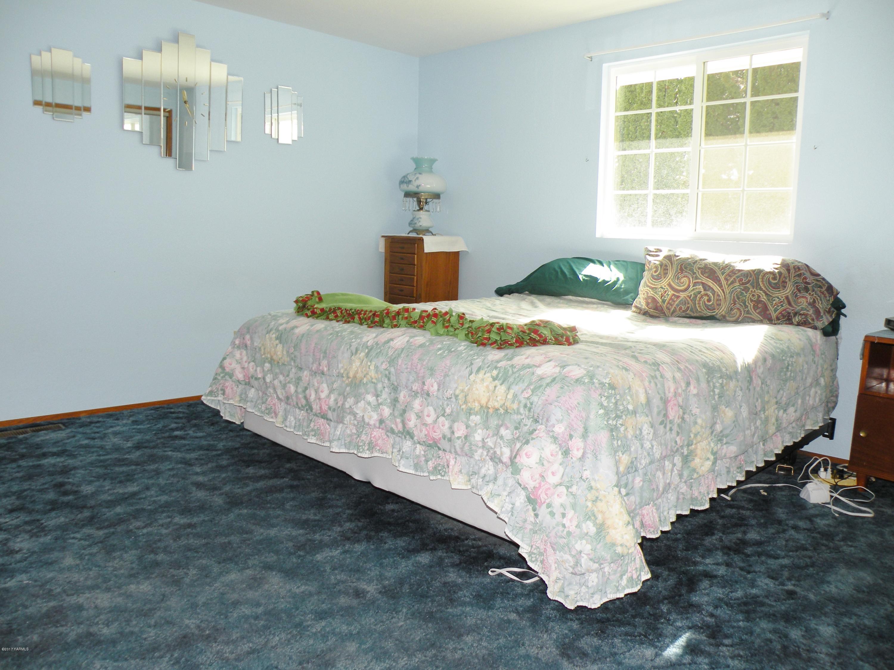 711 Meadowbrook Road Yakima, WA 98903 - Photo 12 of 22 a bed sitting in a bedroom next to a window and a chandelier