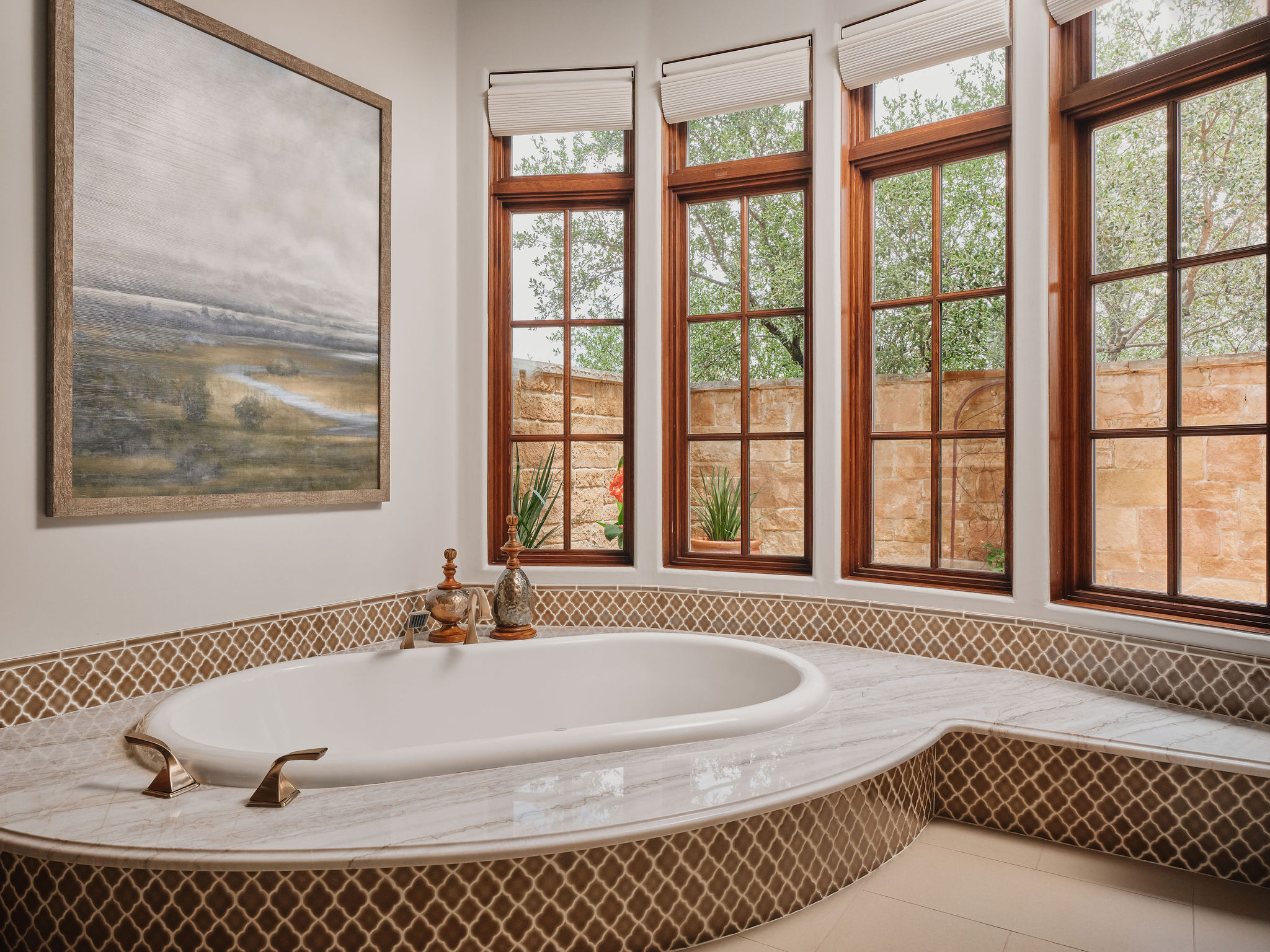 433 Brandon Way Austin, TX 78733 - Photo 18 of 40 An inviting soaking tub with elegant tile and natural wood windows offers a tranquil bathing experience.