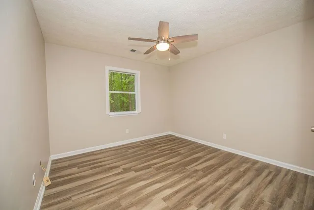 an empty room with windows and fan