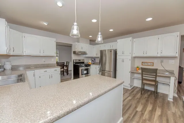 a kitchen with stainless steel appliances kitchen island granite countertop a refrigerator sink and cabinets