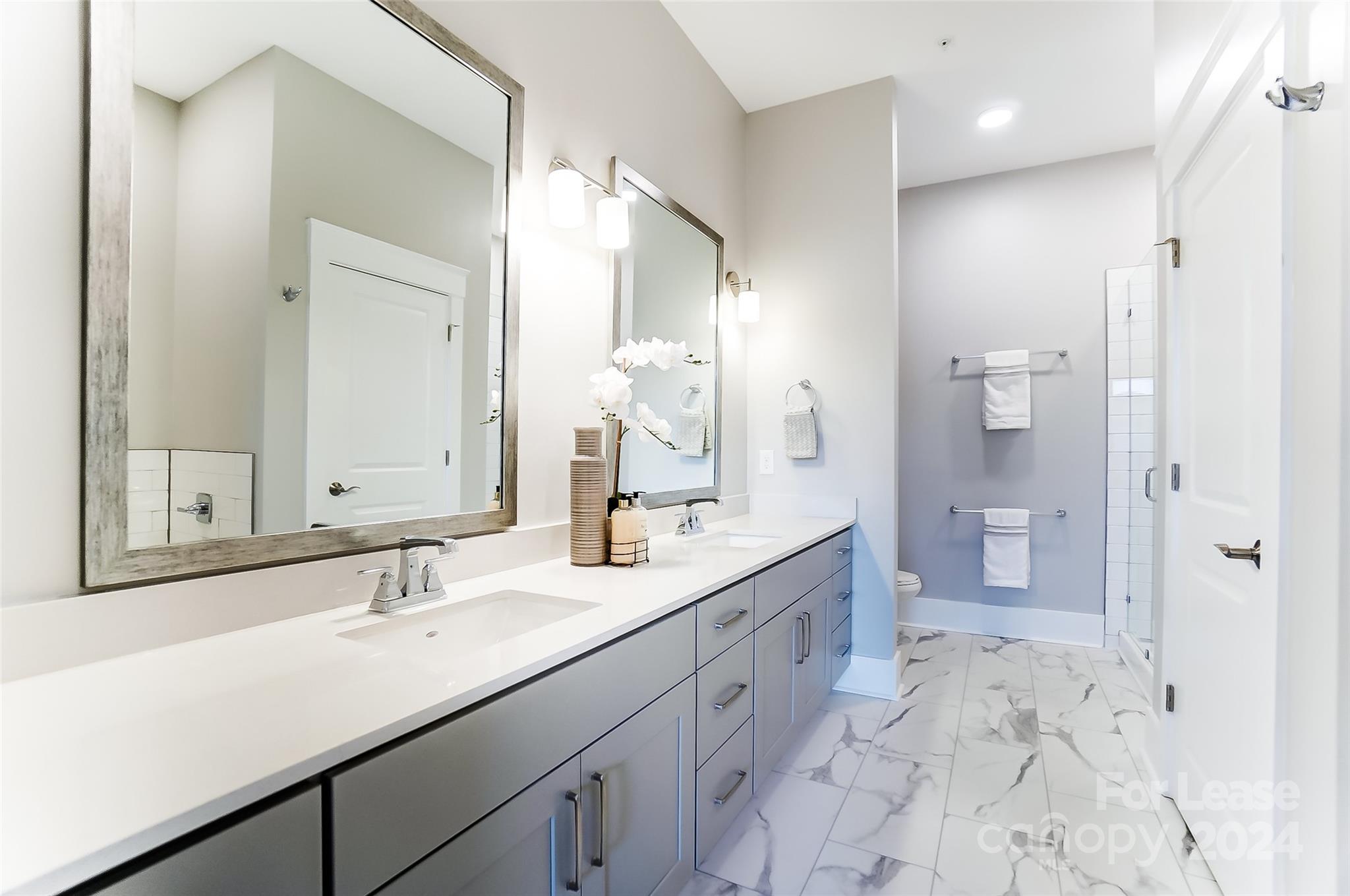 830 Providence Road, Unit 401 Charlotte, NC 28207 - Photo 16 of 24 a bathroom with a shower sink double and mirror