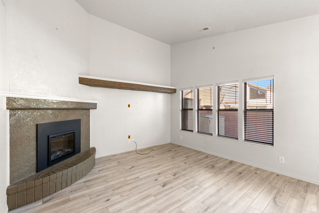301 South 1200th Street East, Unit 31 St. George, UT 84790 - Photo 12 of 21 Unfurnished living room featuring light wood finished floors, a glass covered fireplace, and a high ceiling