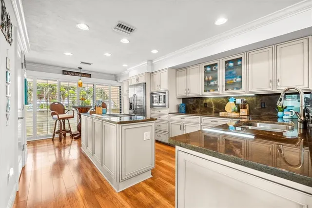 a kitchen with stainless steel appliances granite countertop a refrigerator a microwave oven a dining table and chairs with wooden floor