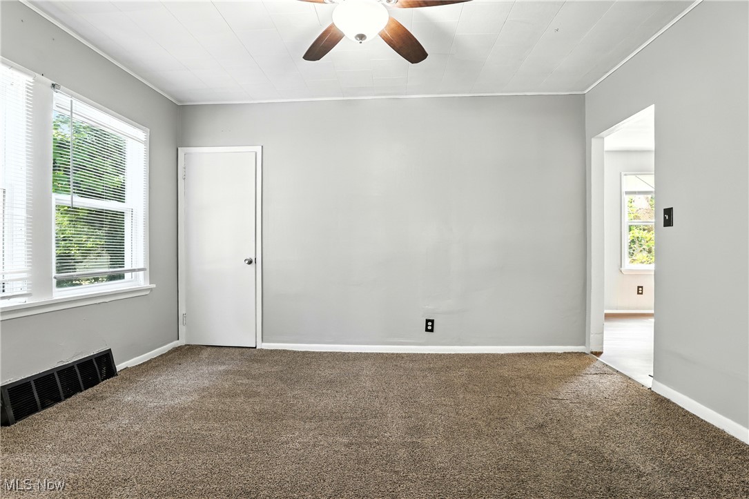 1774 Urbana Road Cleveland, OH 44112 - Photo 8 of 41 Empty room with plenty of natural light, carpet flooring, a ceiling fan, and ornamental molding