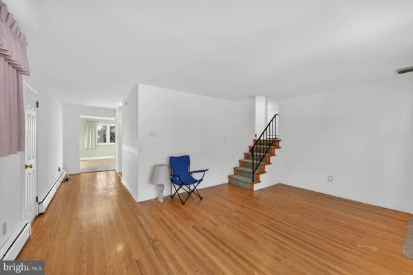 a view of an empty room with wooden floor and stairs