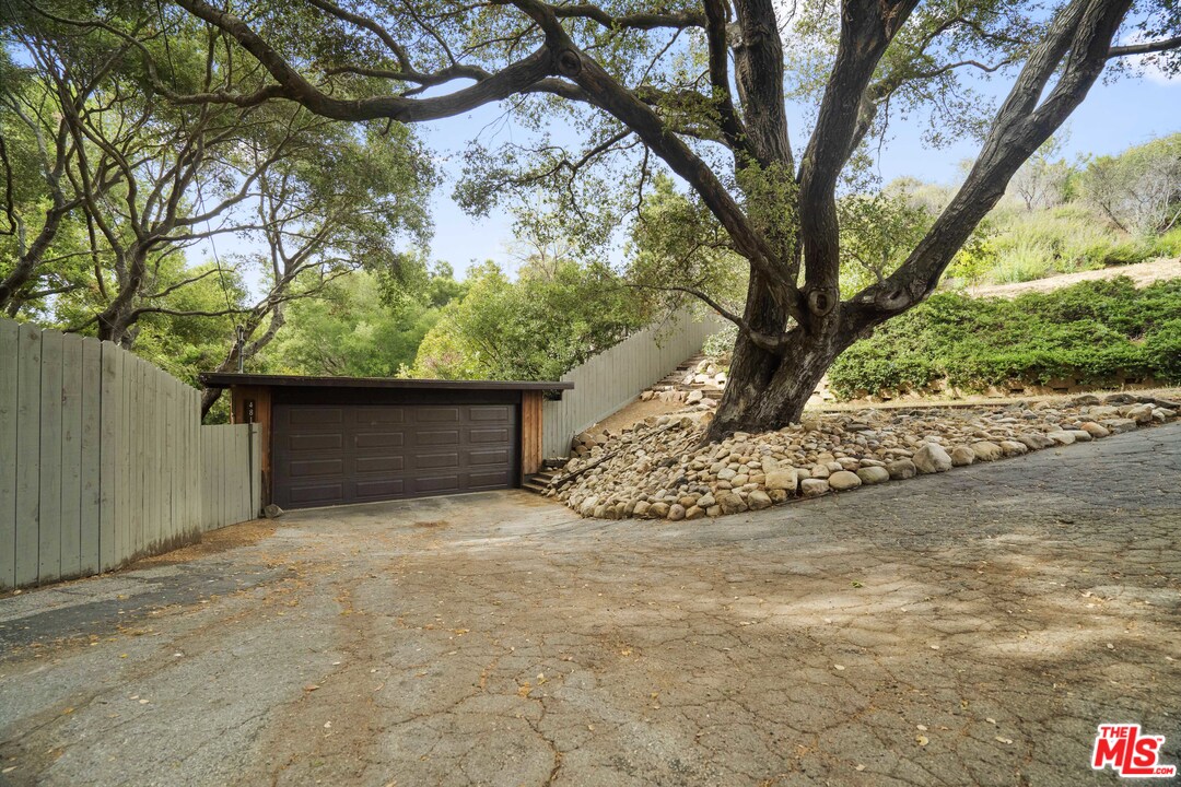 481 Cold Canyon Road Calabasas, CA 91302 - Photo 42 of 44 a view of yellow house with large tree and wooden fence