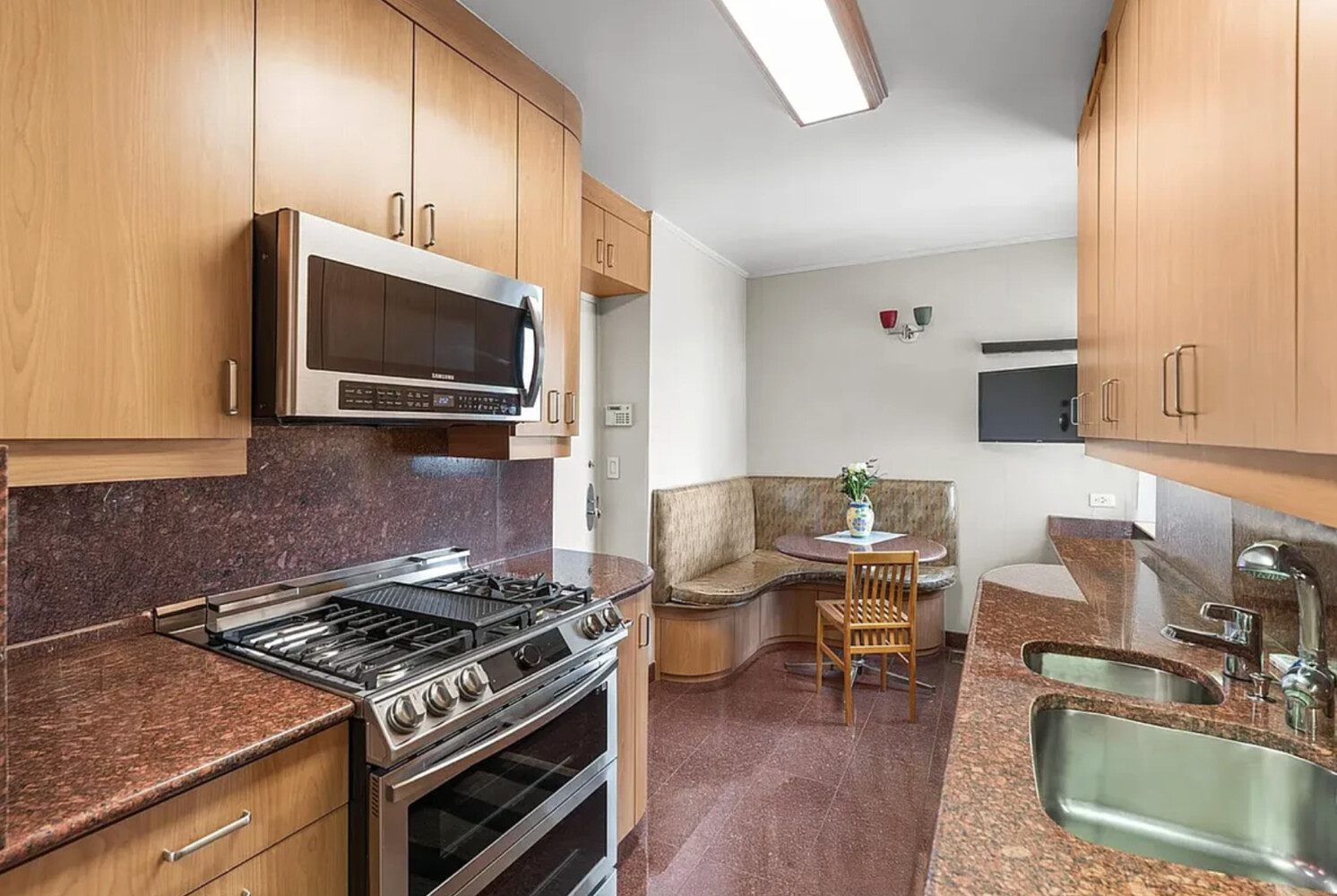 60 East End Avenue, Unit 27B Manhattan, NY 10028 - Photo 5 of 11 a kitchen with a stove a microwave and wooden floors