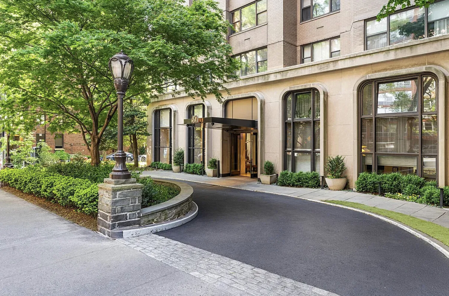 60 East End Avenue, Unit 27B Manhattan, NY 10028 - Photo 7 of 11 front view of a brick house with a yard and large trees