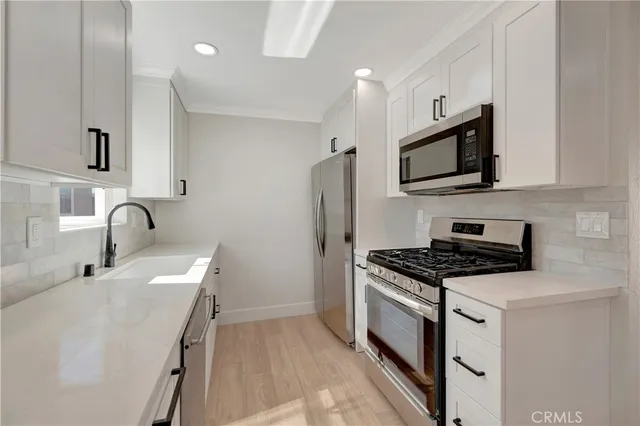 a kitchen with stainless steel appliances a stove microwave and sink