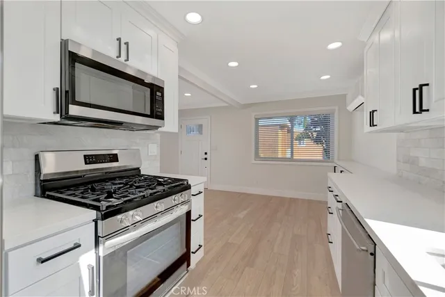 a kitchen with stainless steel appliances granite countertop a stove a sink and a microwave