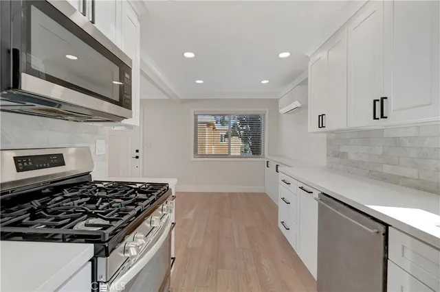 a kitchen with granite countertop stainless steel appliances a stove top oven and wooden floor