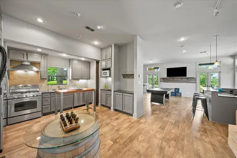a kitchen with stainless steel appliances kitchen island granite countertop a sink refrigerator dining table and chairs