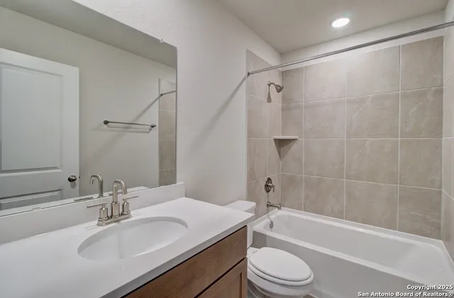 a bathroom with a bathtub shower sink vanity mirror and toilet