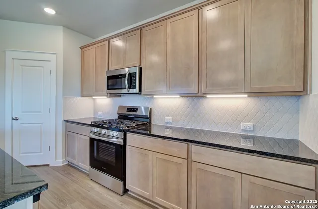 a kitchen with granite countertop cabinets stainless steel appliances and wooden floor