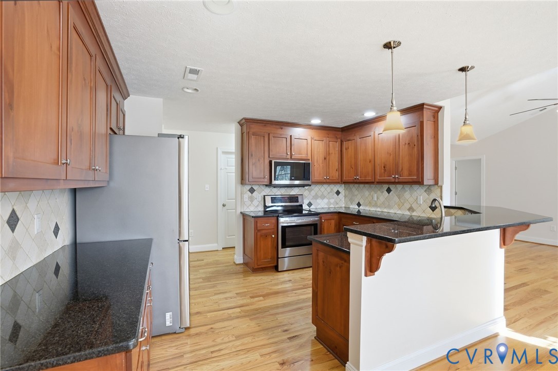 10326 Gould Hill Road Hanover, VA 23069 - Photo 12 of 43 a kitchen with stainless steel appliances granite countertop a refrigerator a sink a stove and a wooden floors