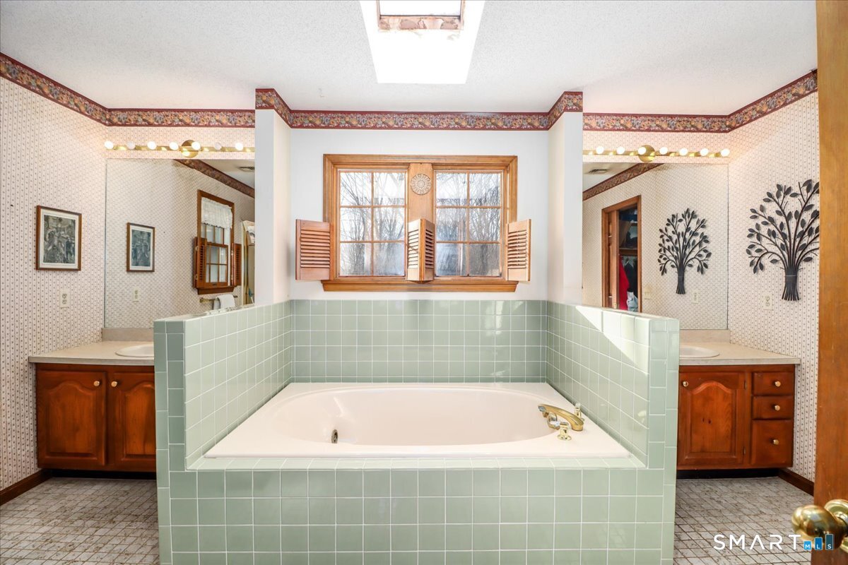 185 Quaker Farms Road Oxford, CT 06478 - Photo 26 of 40 a bathroom with a tub a sink and a mirror