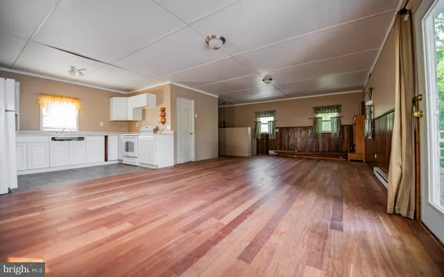 a view of a big room with wooden floor and a kitchen