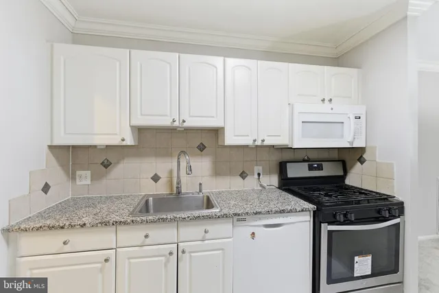 a kitchen with granite countertop white cabinets and a stove