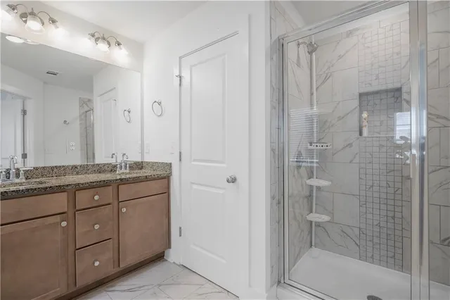a bathroom with a granite countertop sink a mirror and a shower